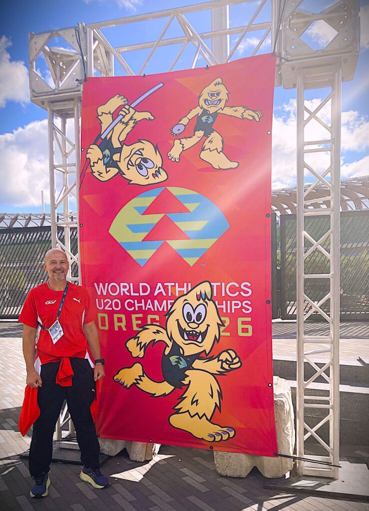 Mst. Michael G. Leitner vor dem Veranstaltungsplakat der World Athletics U20 Championships in Oregon.